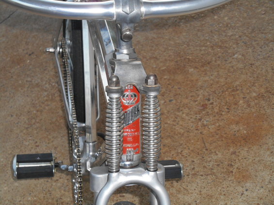 Chrome handlebars and red bicycle fork with visible springs and pedals