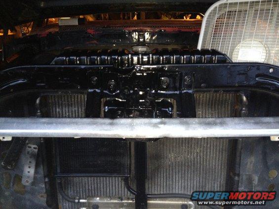 Close-up of vehicle radiator and oil cooler assembly with a fan in the background