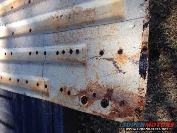 Rusted metal panel with rows of holes and blue markings
