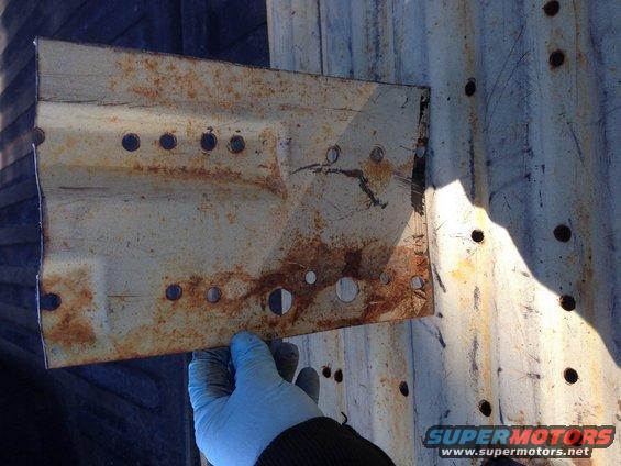 Rusted metal bracket with multiple holes, held by a gloved hand