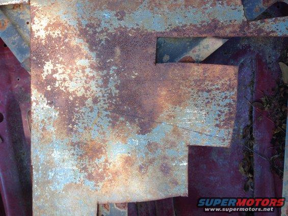 close-up of heavily rusted metal panel with peeling blue paint over red primer
