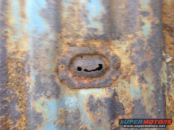 Rusted metal panel with oval cutout resembling a face