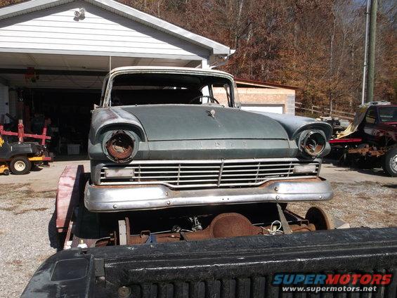 Front view of a 1957 Ford Custom Sedan being transported on a trailer, missing headlights