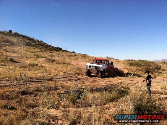 White and red off-road truck driving on dusty terrain