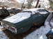 1974 Dodge Challenger - This green car sits in a snowy junkyard with other vehicles.