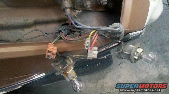 Close-up of exposed wiring and light bulb sockets on a vehicle's rear end