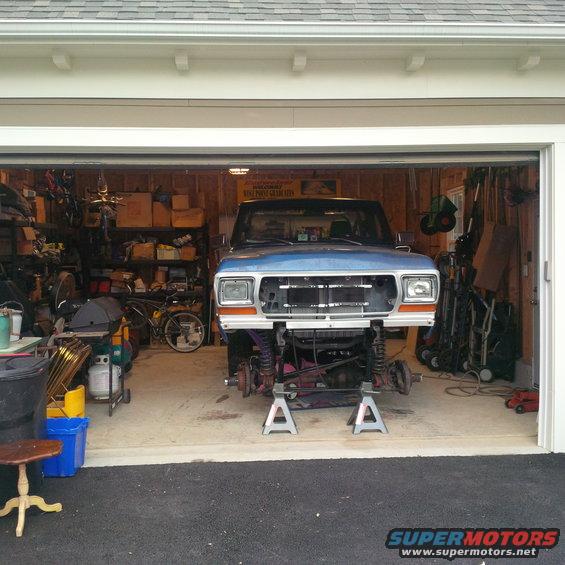 1978 Ford Bronco front end with grille removed, raised on jack stands in a garage