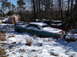 1974 Dodge Challenger - A green car sits partially covered in snow amidst trees and other objects.
