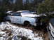 1974 Dodge Challenger - A light blue coupe sits in a snowy junkyard, its hood and roof covered in snow, with other vehicles visible in the background.