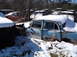 1974 Dodge Challenger - Several old cars sit in a snowy junkyard, one light blue sedan is partially visible.