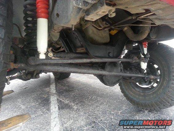 Undercarriage view of a 4x4 with red and white shocks, showing the steering and suspension components