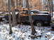 1974 Dodge Challenger - Abandoned blue pickup truck sits in a snowy forest with other vehicles nearby.