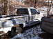 1974 Dodge Challenger - A white pickup truck sits abandoned in a snowy, wooded area next to another vehicle.
