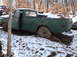 1974 Dodge Challenger - A green pickup truck sits in a snowy wooded area, with another vehicle partially visible in the background.