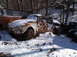 1974 Dodge Challenger - A rusty Volkswagen Beetle sits abandoned in the snow, surrounded by other vehicles in a forest.