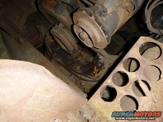 Engine pulleys and belts on a rusty metal surface, with a Supermotors.net watermark