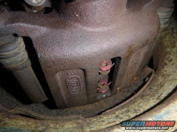 Rusty brake caliper with visible Ford logo and part numbers