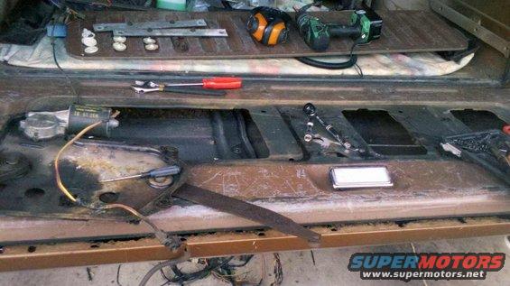 disassembled car door interior with window mechanism and tools