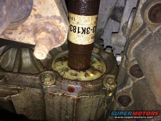 Close-up of a driveshaft entering a housing with a yellow seal. Label on driveshaft reads '3-3K183'