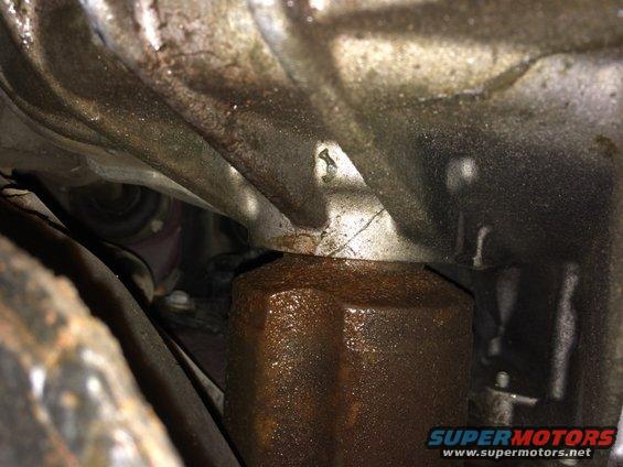 rusted oil filter and transmission housing with visible oil leaks
