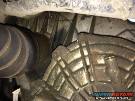 Close-up of a car's driveshaft boot and transmission housing