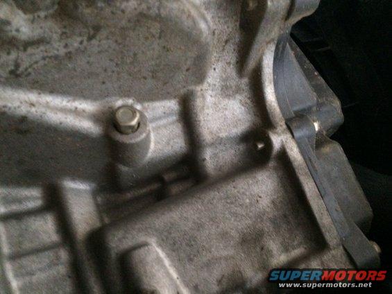 Close-up of a gray metal engine block with a bolt and a black rubber seal