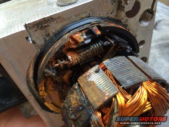 Close-up of a corroded electric motor rotor with visible copper windings and damaged components