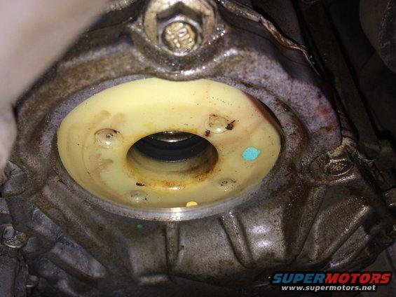 Close-up of a yellow seal and metal housing with bolts, showing some dirt and blue paint marks