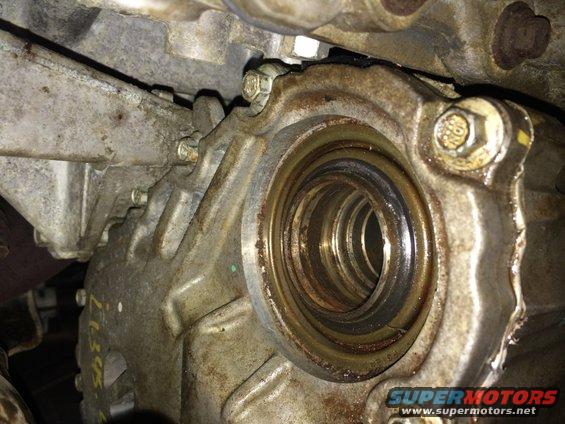 Close-up of a greasy, metallic vehicle transmission housing with a seal