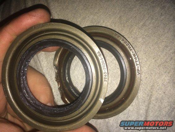 Two metal seals with rubber gaskets, one damaged, held by a hand