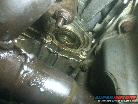 Close-up of a leaky engine component, possibly a seal or gasket