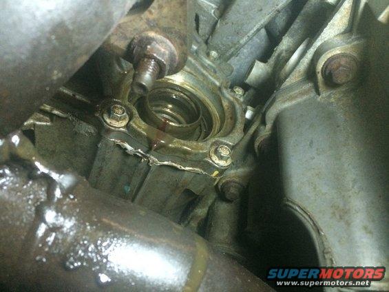 Close-up of a leaking engine oil seal with visible fluid and metal components