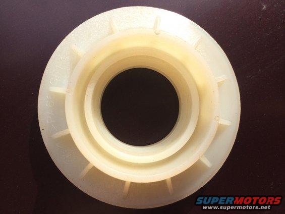 Cream-colored plastic part with concentric rings and radial fins. Text visible