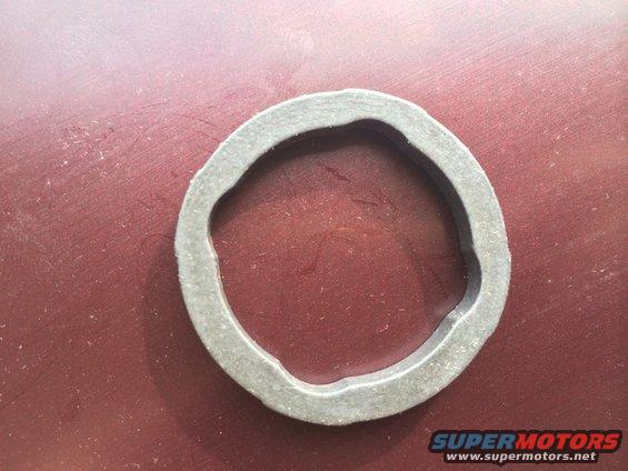 Close-up of a rubber gasket on a red surface. Supermotors.net logo in the bottom right