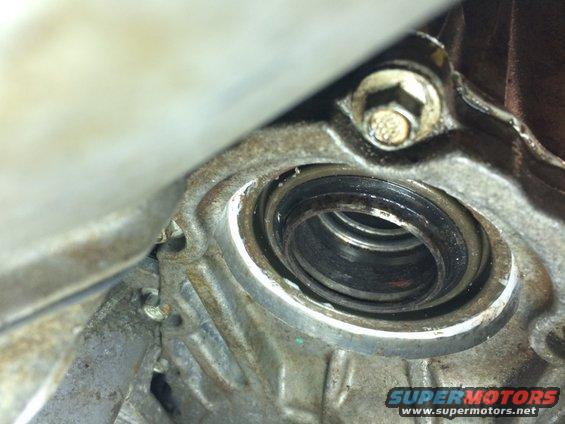 Close-up of a worn seal within a metal housing, with visible grease and dirt