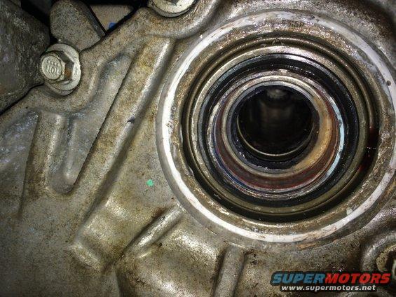 Close-up of a worn seal and bearing assembly within a metal housing, likely part of a vehicle's transmission or drivetrain