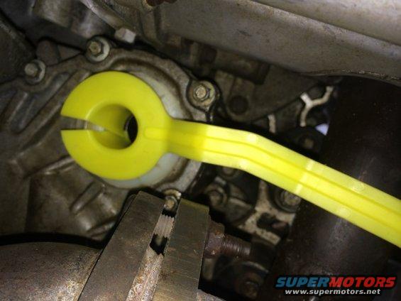 Yellow tool on vehicle transmission housing, close-up