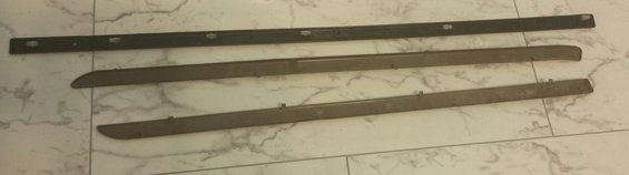 Three automotive trim pieces laid out on a tiled surface