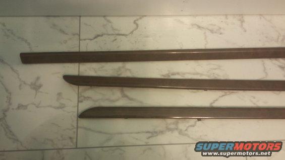 Three wood grain trim pieces on a marble-patterned surface