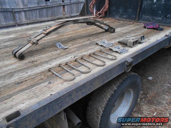 Leaf springs and U-bolts laid out on a wooden flatbed truck deck