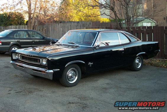 Black coupe parked in a driveway, front quarter view. Chrome bumper and grille