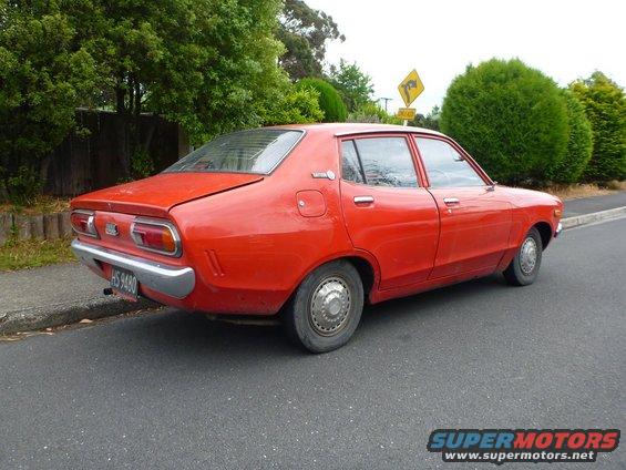 red sedan parked on street, rear quarter view. License plate HS 9480
