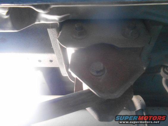 Underside of a vehicle showing suspension components and frame structure, with a bright light source illuminating the scene