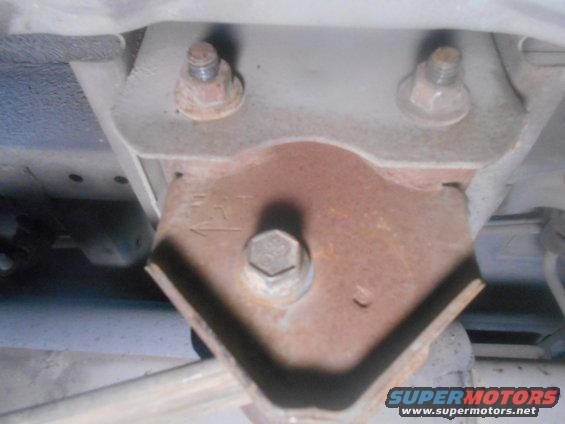 Close-up of a rusted metal bracket with bolts, showing an arrow indicator