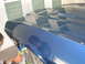 1972 Ford Ranchero - A person works on the freshly painted blue hood and fender of a 1972 Ford Ranchero.