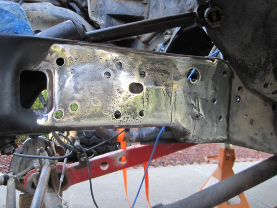 Close-up of a vehicle's metal frame undergoing repair, showing welds and drilled holes