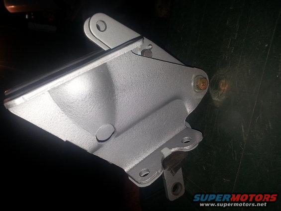 Close-up of a silver metal engine bracket with bolt holes