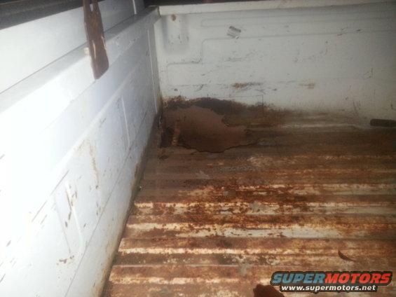 White truck bed interior with significant rust on the floor and lower side panels