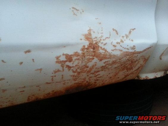 White truck fender with significant rust damage near the wheel well
