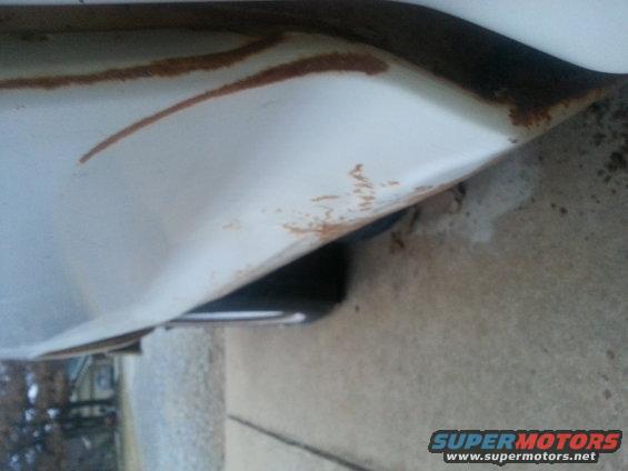 White truck fender with rust spots and visible tire